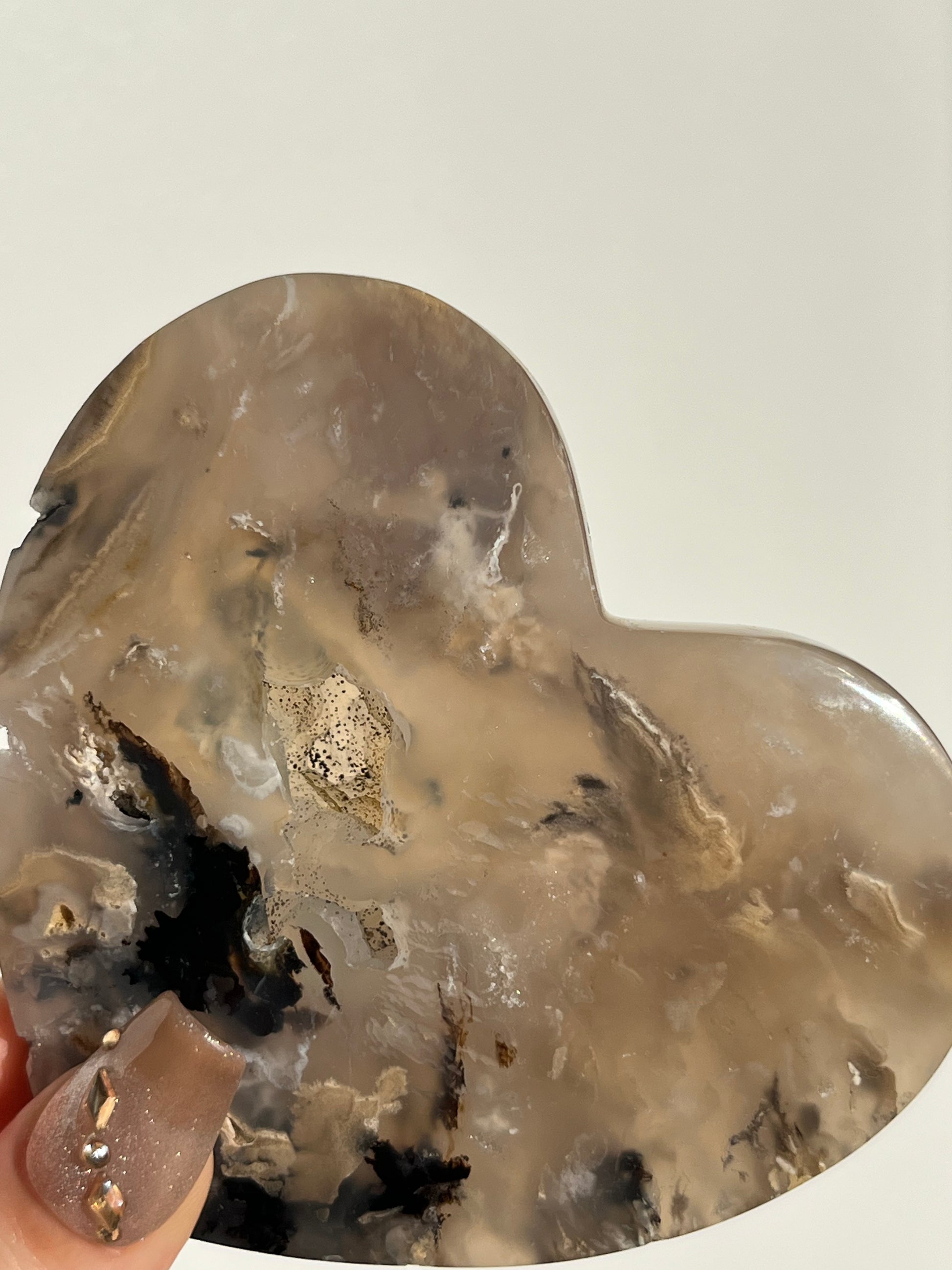 Heart-shaped crystal with embedded minerals on a plain background